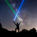 man holding green and blue flashlights