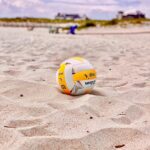 yellow and white volleyball on white sand during daytime beach volley