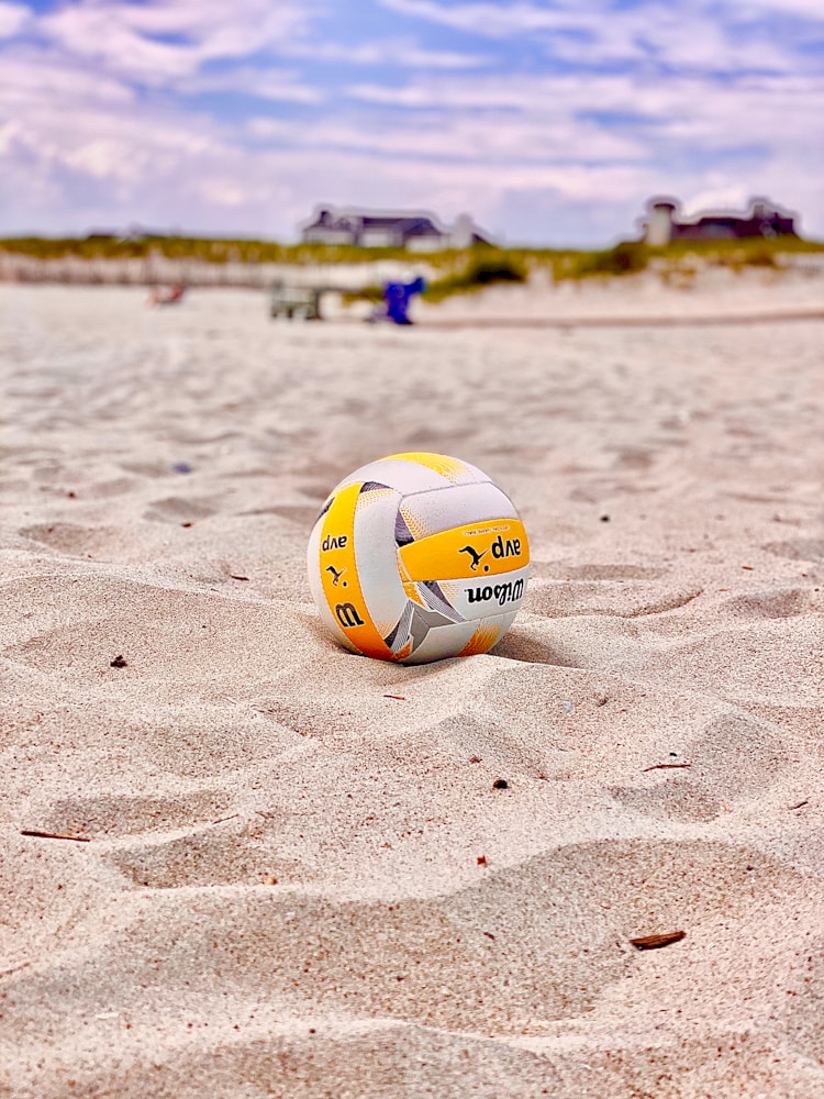 yellow and white volleyball on white sand during daytime beach volley