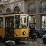 a yellow trolley car on a city street, referendum blocco moto Milano