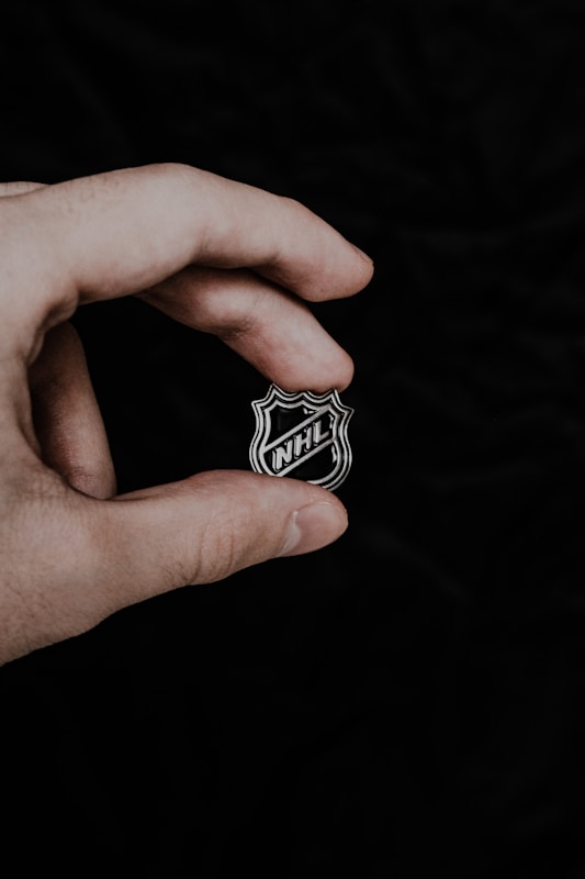 a person holding a badge in their hand, stelle NHL Milano-Cortina 2026