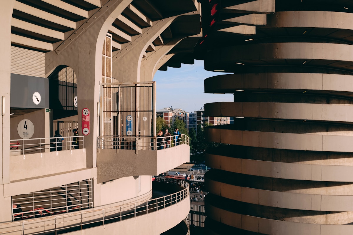 a tall building with a balcony next to a parking lot