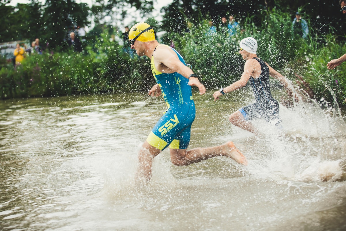 man in blue shorts running on water during daytime gare di triathlon a Milano
