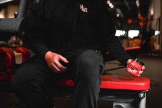 a man sitting on top of a bench holding a can integratori sportivi