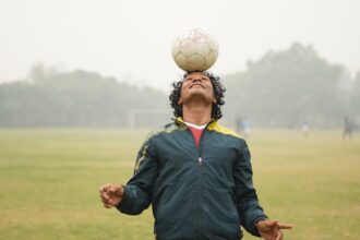 man in blue jacket holding white soccer ball