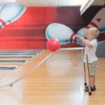 man in white shirt and pants holding white and red balloon bowling per bambini e ragazzi a Milano