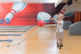man in white shirt and pants holding white and red balloon bowling per bambini e ragazzi a Milano