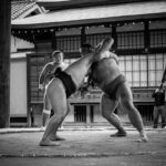 A couple of people that are standing in the street il sumo come disciplina sportiva
