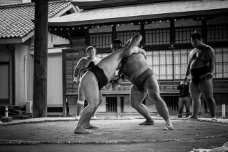 A couple of people that are standing in the street il sumo come disciplina sportiva