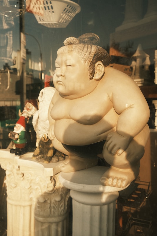 a statue of a sumo wrestler sitting on a pedestal