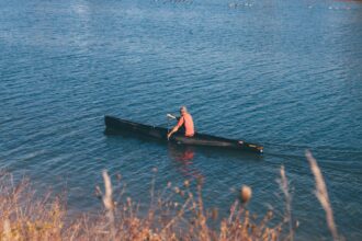 woman in black and red dress sitting on black boat on sea during daytime canoa a Milano