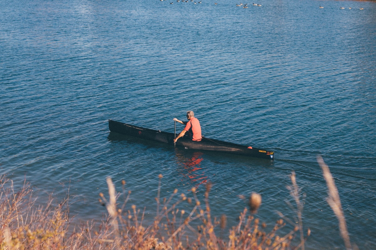 woman in black and red dress sitting on black boat on sea during daytime canoa a Milano
