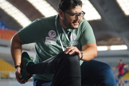 a man in a green shirt is doing something on another man's leg