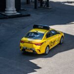 A yellow Uber taxi driving on a city street, shown from above.