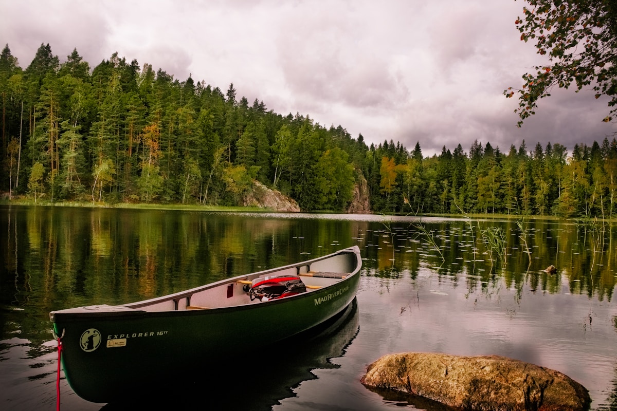 red and white canoe on lake near green trees under white clouds during daytime canoa a Milano